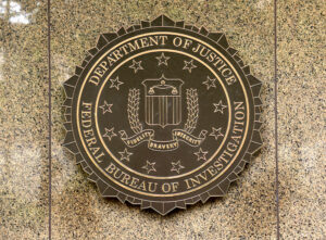 FBI seal on brown marble wall at the US Department of Justice headquarters.