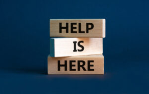 Help Is Here written on three stacked wooden blocks.